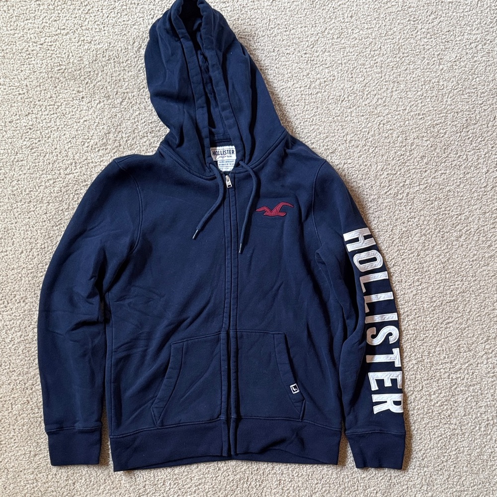Hollister Navy Zip Hoodie with Red Logo and White Sleeve Text